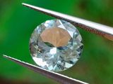 quelqu'un tient une pince dans laquelle est sertie un diamant bleu