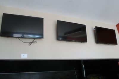 trois téléviseurs fixés au mur au-dessus d'une cheminée
