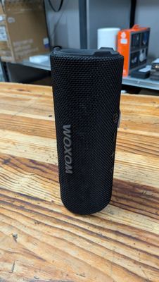 un gros plan d'une enceinte noire posée sur une table en bois