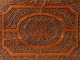 carvings on the back of a wooden box with a monogram on it