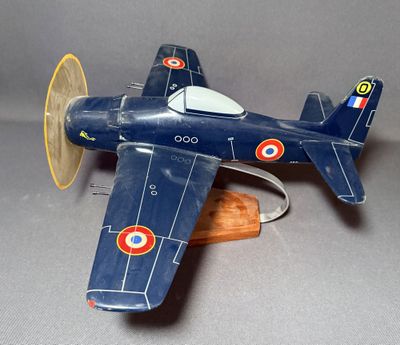 un petit avion en bois posé sur un socle en bois