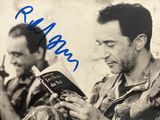 une vieille photo montrant un homme en train de lire un livre, avec un autre homme assis à côté de lui