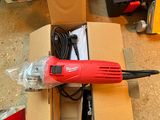une perceuse filaire rouge dans une boîte en carton posée par terre