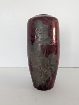 un vase violet orné d'une fleur, posé sur un fond blanc