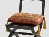 une chaise noire avec un coussin rouge et un pompon doré dessus