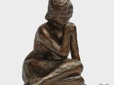 un gros plan sur la statue d'une personne assise par terre