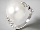 une photo d'une bague en perle blanche et diamants posée sur une table