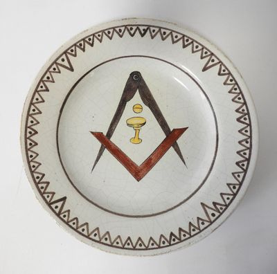 une assiette ornée d'un symbole maçonnique, posée sur une table