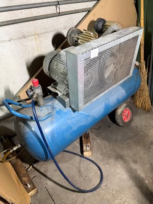 un compresseur d'air bleu posé dans un garage à côté d'une pile de cartons