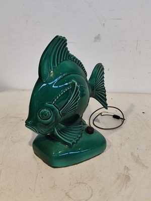 une statue de poisson verte posée sur une table, à côté d'un cordon