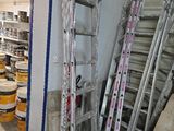 a room with a ladder and several buckets of paint on the floor