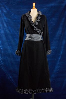 une robe noire posée sur un mannequin, devant un fond bleu