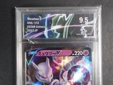 two pokemon cards in plastic cases on a black surface