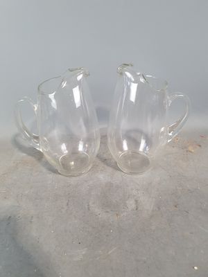 pair of clear glass vases sitting on top of a cement floor