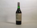 une vieille bouteille de vin posée sur une table blanche