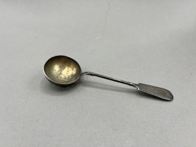 an old spoon sitting on top of a table next to a knife