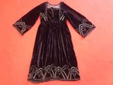 a black velvet dress with gold embroidery on the shoulders