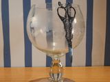 a glass with a pair of scissors in it sitting on a table