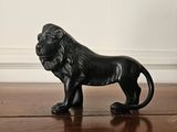 a black lion figurine sitting on a wooden floor
