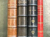 plusieurs vieux livres sont alignés sur une étagère, les uns à côté des autres