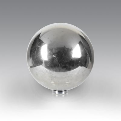 a shiny silver ball on a stand on a white surface