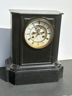 a black clock with a gold face sitting on a table