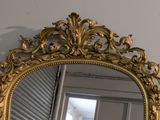 a gold mirror hanging on the wall next to a window