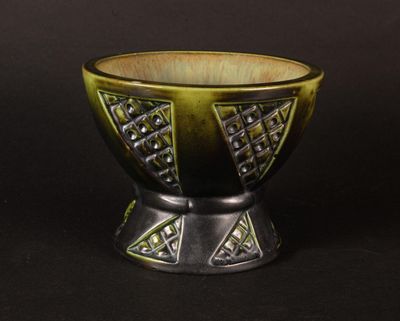a green and black bowl sitting on a black surface