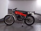 a red motorcycle parked in a parking garage next to a white wall