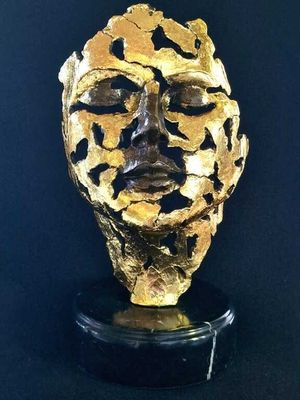 a close up of a gold mask on a black surface