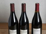 three bottles of wine are lined up on a wooden table