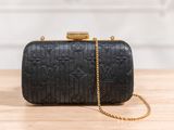 a black clutch bag sitting on top of a wooden table