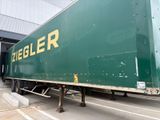 un grand camion vert garé devant un immeuble