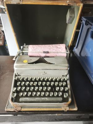 an old typewriter sitting on top of a table next to a blue box