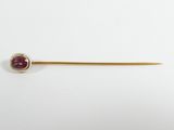 a close up of a gold stick with a red stone on it