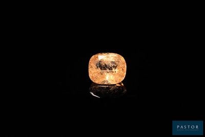 a yellow diamond on a black surface in the dark