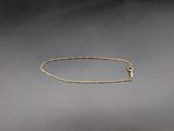 un bracelet en chaîne d'or muni d'un fermoir, sur fond gris