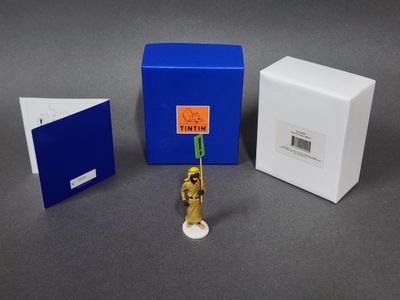 une petite figurine située à côté d'une boîte bleue et d'une boîte blanche