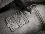 a black and white photo of an old fire hydrant with a hammer sticking out of it