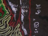 chalk drawing of a woman ' s face on a black shirt with a green and red design