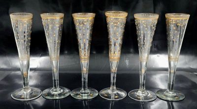 quatre flûtes à champagne ornées de motifs dorés, posées sur une table