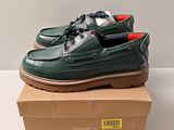 chaussures bateau en cuir vert pour homme, à semelles rouges, posées sur une boîte en carton