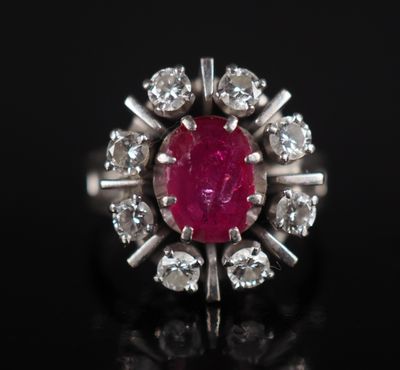 gros plan d'une bague avec une pierre rouge entourée de diamants blancs