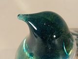 a glass bird sitting on top of a silver plate