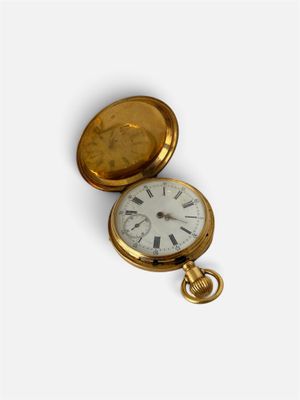 une montre de poche en or avec un cadran blanc sur une surface blanche