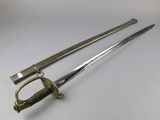 two swords are laying on a white surface with one sword in the foreground