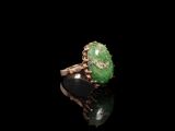 un gros plan d'une bague ornée d'une pierre verte sur un fond noir