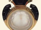 a black and gold perfume bottle with a white face on it