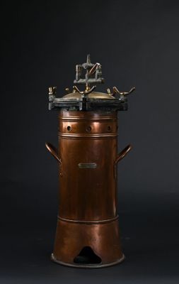 une cafetière ancienne plaquée cuivre sur fond noir