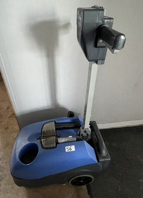 a blue and black vacuum on the floor next to a wall